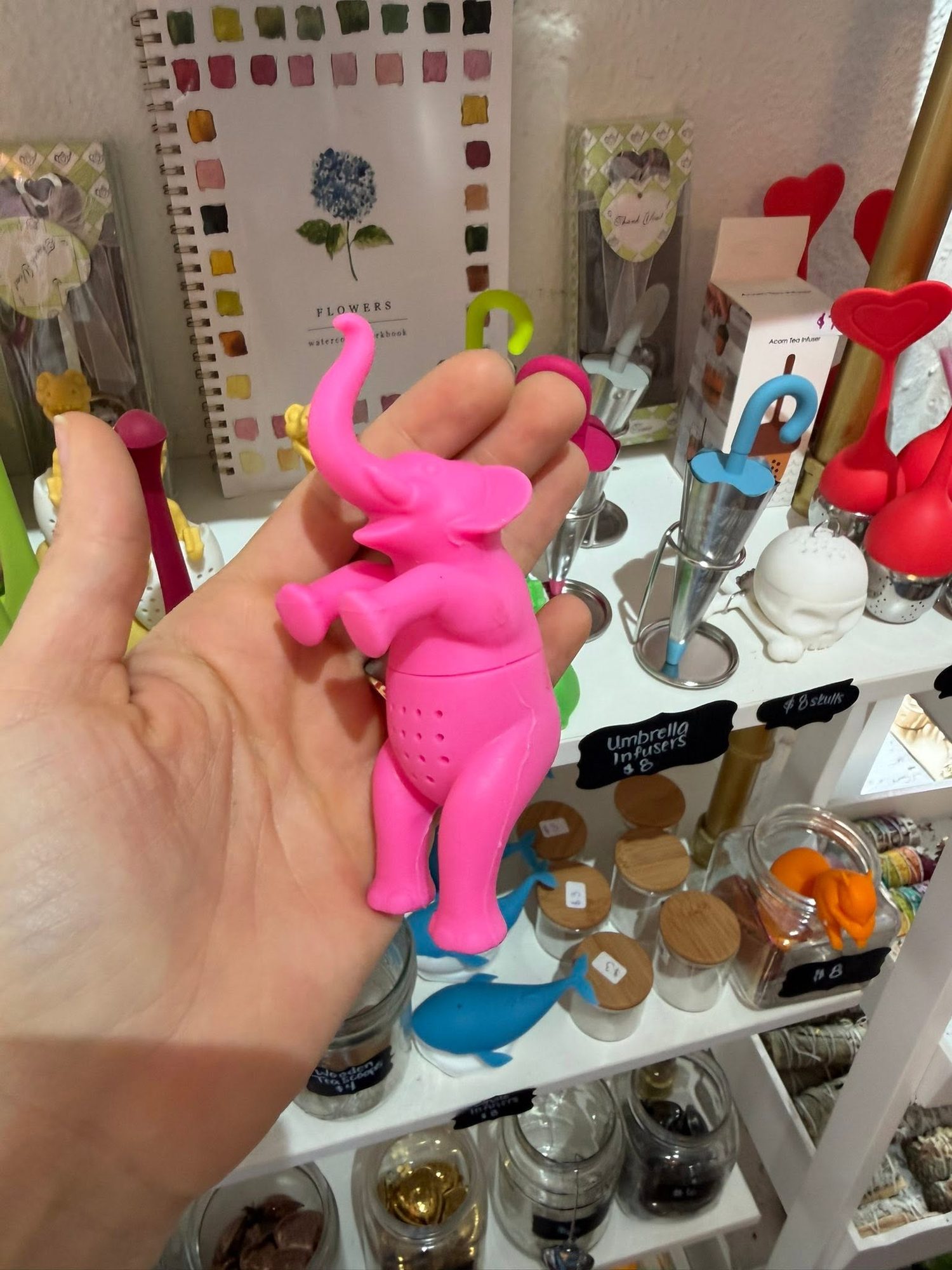 Hand holding a pink elephant-shaped tea infuser